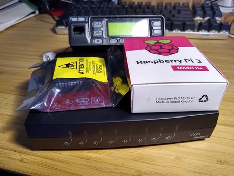 A dialup modem, on top is a raspberry pi in box, TNC-Pi in bag, and a small radio