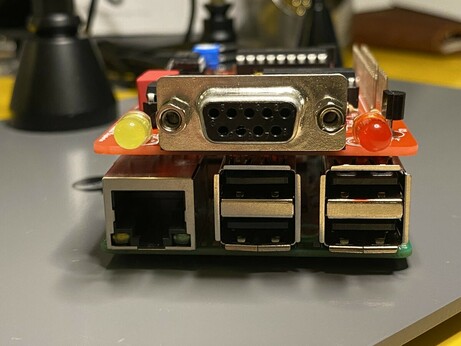 Front view of the TNC-Pi on top of the Raspberry Pi 3B. It has two LEDs and a DB9 connector for connection to a radio.