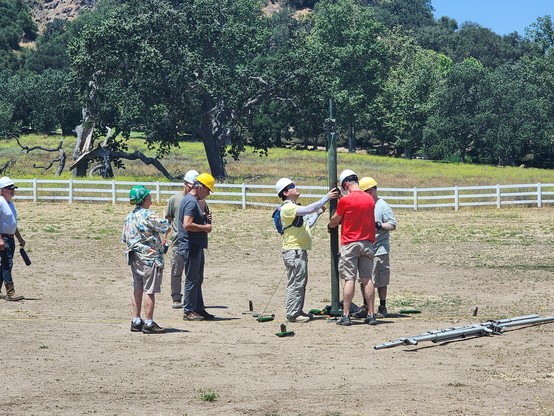 Group of people erecting a military-style radio mast